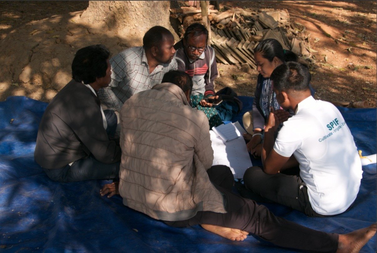An SPIF field officer reviewing survey documents with community members on-site