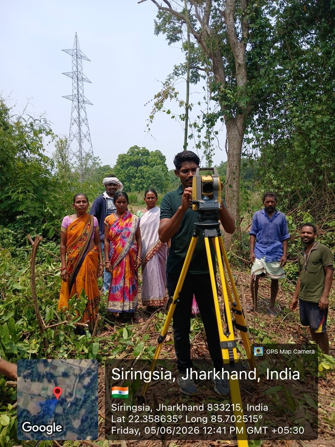SPIF surveyor operating a total station with community members looking on