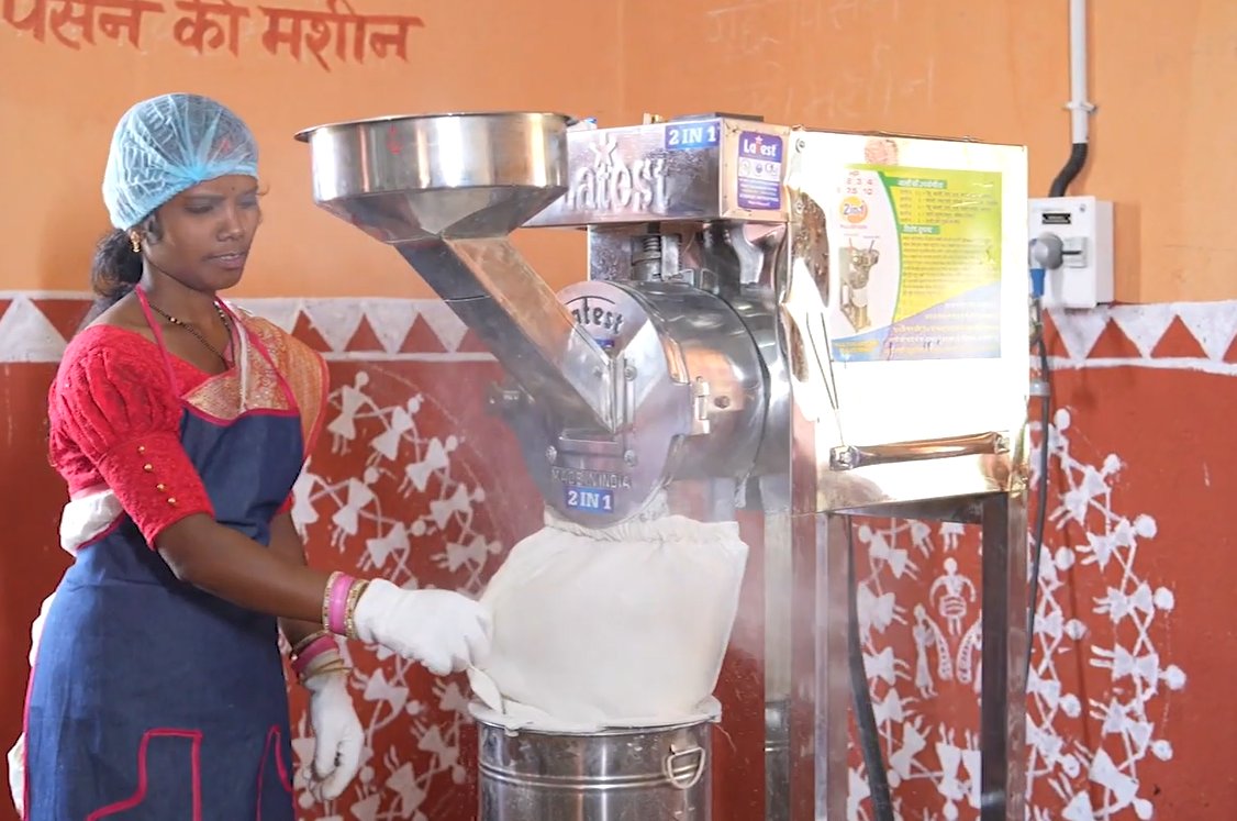 A woman operating a flour milling machine as part of a rural enterprise unit