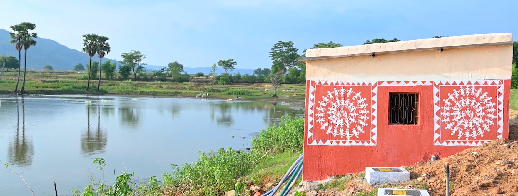 A farm pond with a pump house on its bank, used for water storage and irrigation supply
